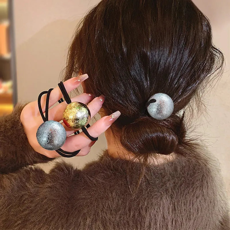 Resin hair band with electroplated gold finish, round head rope style, on a plain background