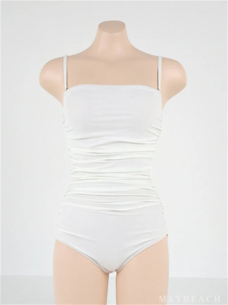 Sling style one-piece swimsuit for women with belly pleats in blue, white, yellow, or black.