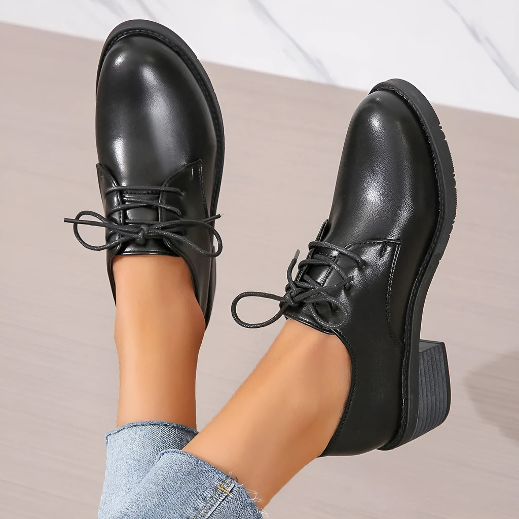 Black women's low-top work shoes with a chunky mid heel and soft rubber sole.
