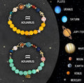 Set of twelve natural stone beaded bracelets laid out, each with a different zodiac sign charm.