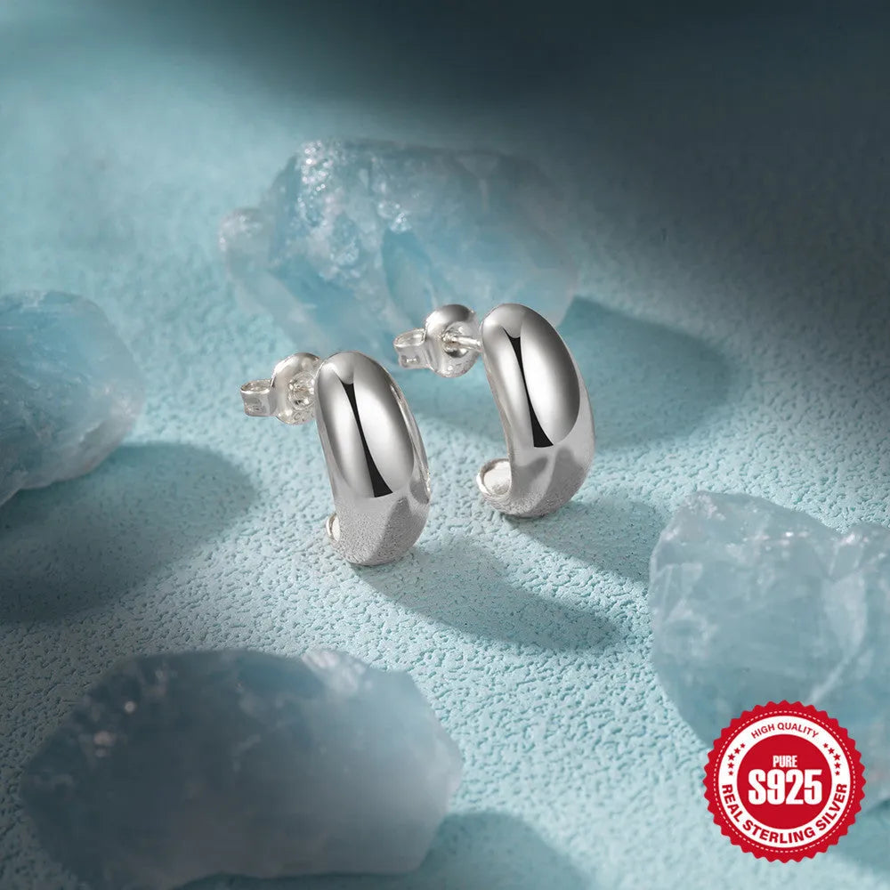 Close-up of a glossy C-shaped sterling silver stud earring with a post back, shown on a neutral background.