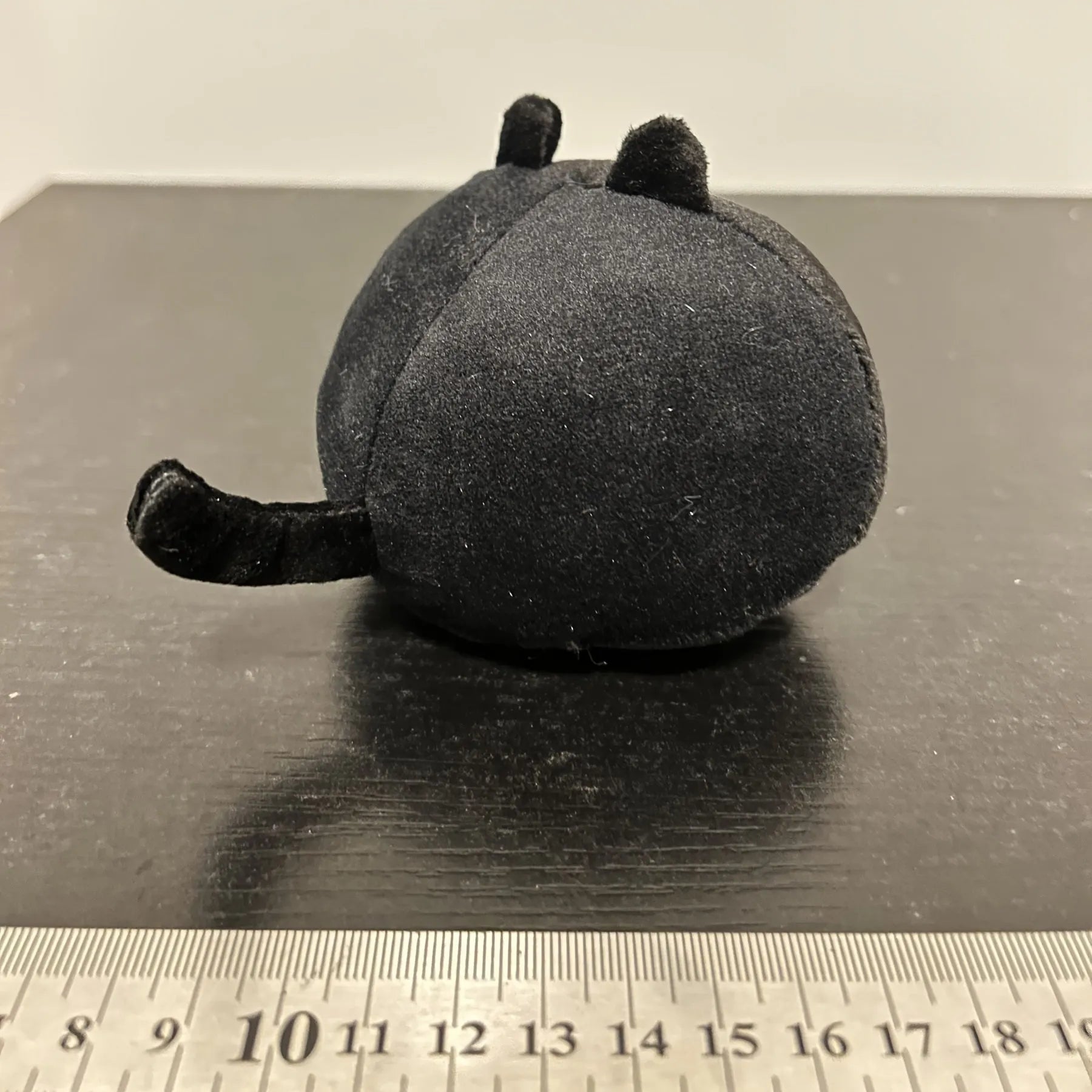 Fluffy black cat plush toy stuffed animal cushion on a sofa