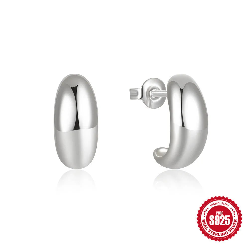 Close-up of a glossy C-shaped sterling silver stud earring with a post back, shown on a neutral background.