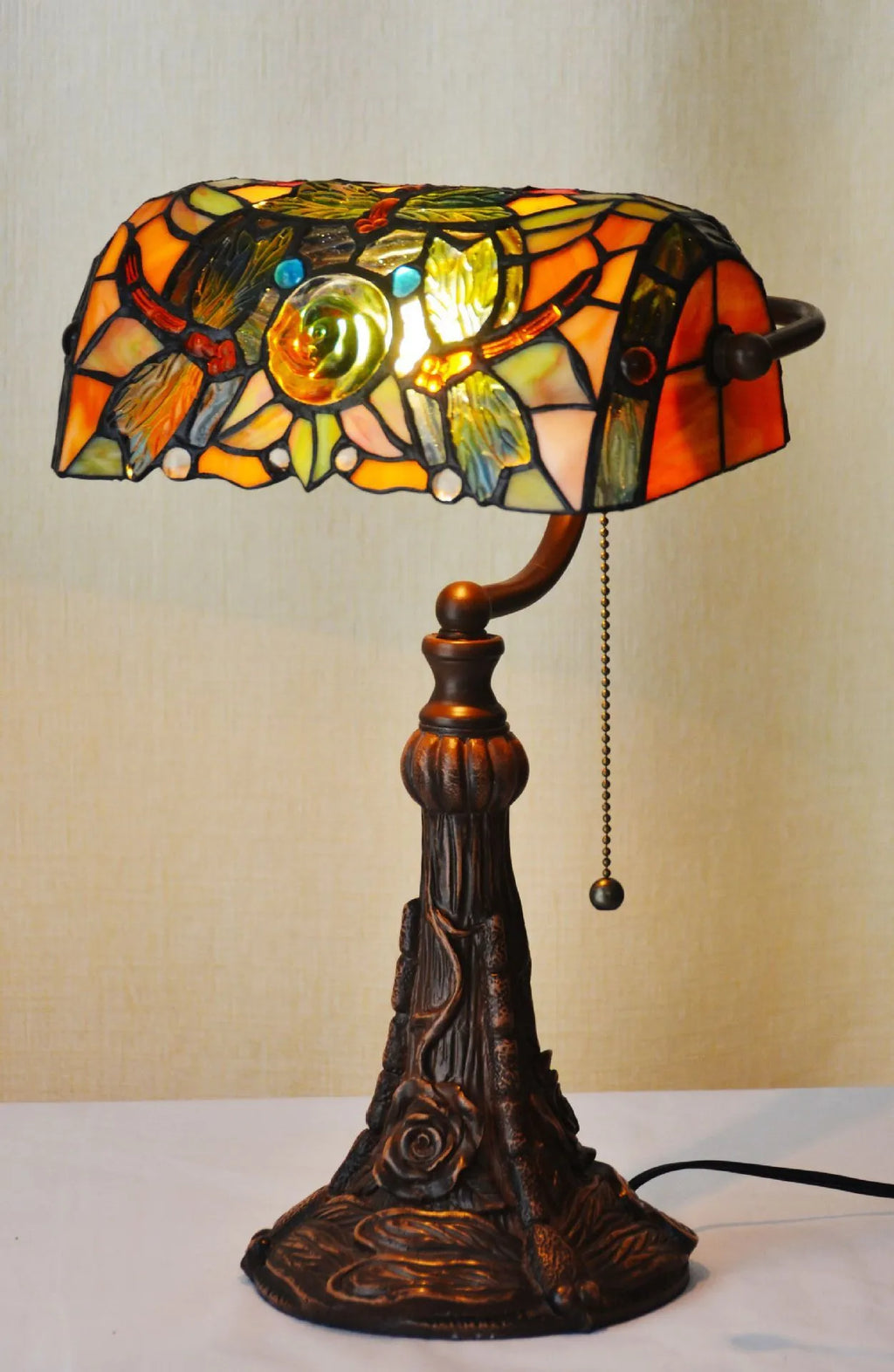 Tiffany table lamp with coloured glass lampshade and stained glass resin base on wooden desk