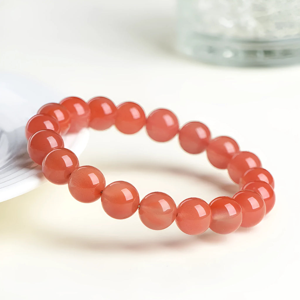 Natural South Cherry Red Agate polished bead bracelet shown in a scattered design on a wrist.