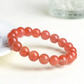 Natural South Cherry Red Agate polished bead bracelet shown in a scattered design on a wrist.