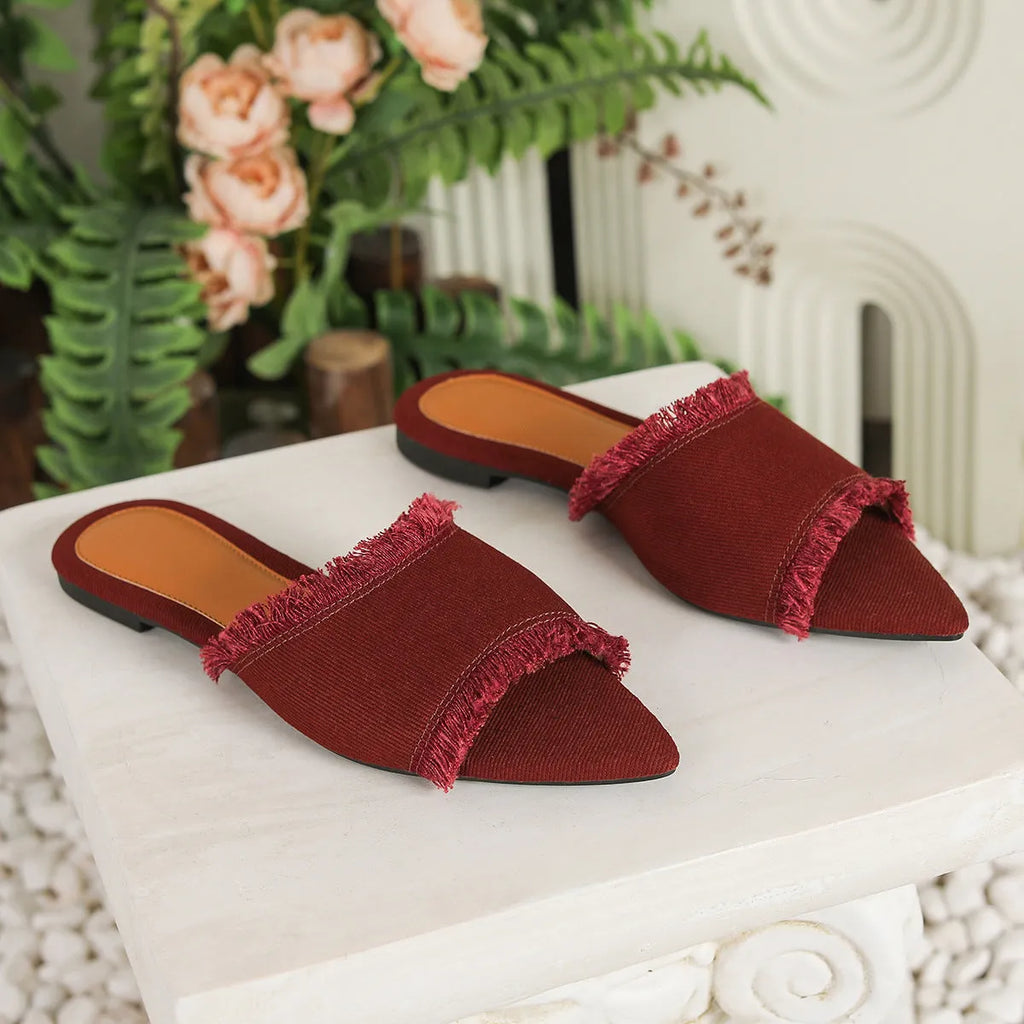 Women's denim flat slipper with leather lining, PVC sole, and a decorative tassel in a solid colour.