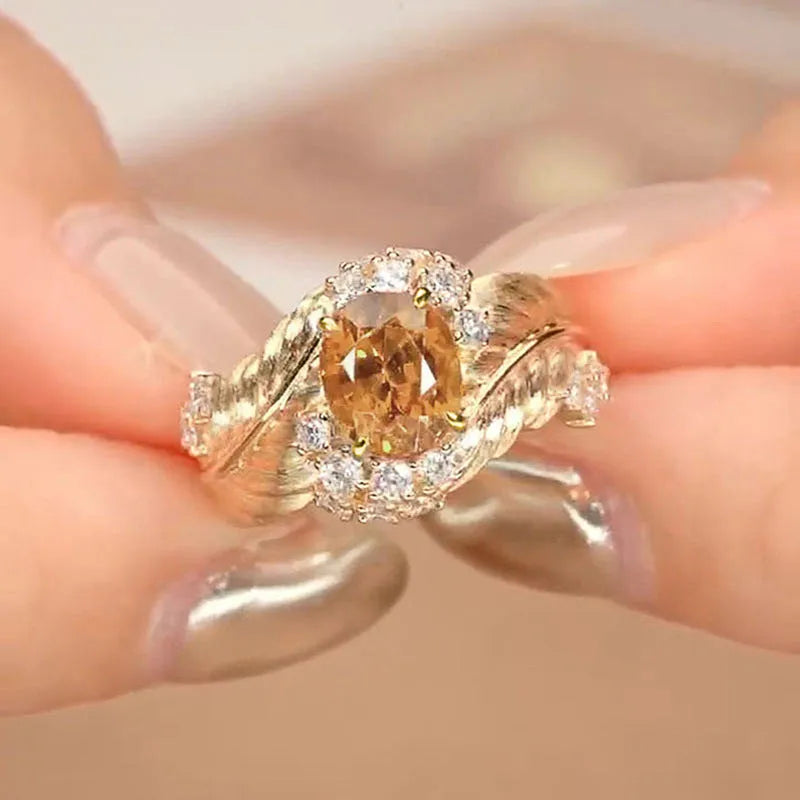 Gold coloured women's ring with embossed feather design and yellow zircon stones.