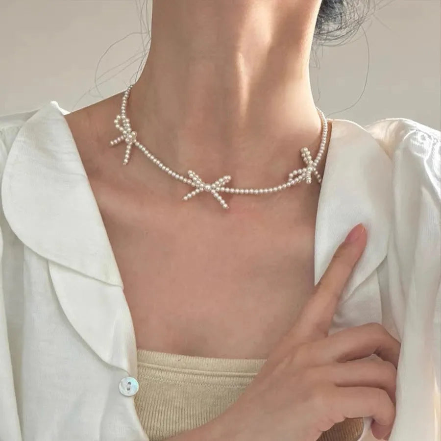 White adjustable pearl necklace with bow detail measuring 31-40cm